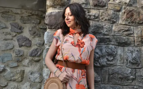 Donna con abito floreale rosa antico, cinturone marrone e borsa rotonda. I colori vivaci del vestito sono perfetti per abbinare al rosa antico.