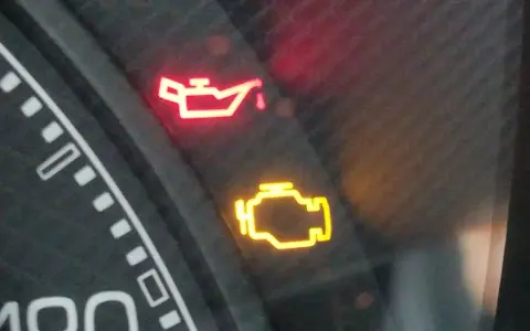 Cruscotto auto con spia dell'olio accesa in rosso e spia motore gialla. Urgente controllo.