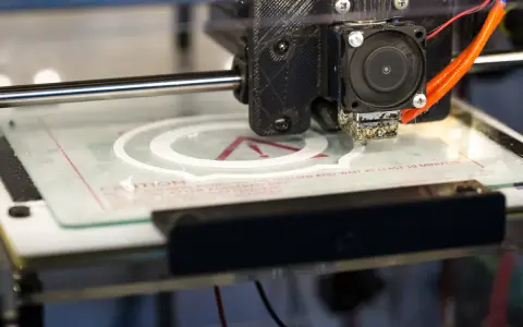 Głowica drukarki 3D tworzy biały okrąg na szklanej platformie. To część projektu drukarki 3d.