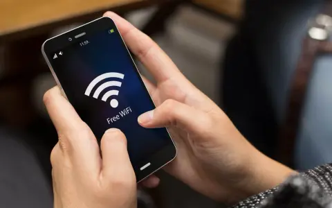 Person versucht, das Handy mit dem WLAN zu verbinden, aber es klappt nicht. Das WLAN-Symbol leuchtet auf dem Bildschirm.