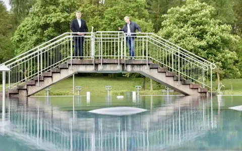 Zwei Männer stehen auf einer Brücke über dem Wasser des Freibad Porta Westfalica.