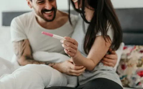 Ein Paar hält einen Schwangerschaftstest, der positiv ist. Was zeigt ein Ovulationstest an, wenn man schwanger ist? Zwei rosa Linien.