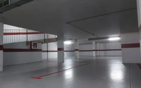 Suelo de garaje recién pintado, con líneas rojas y grises que marcan las plazas.