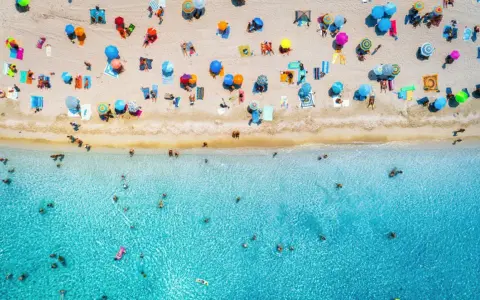 Un'affollata spiaggia di Rimini mare, con ombrelloni colorati e bagnanti che si godono il sole e il mare cristallino.