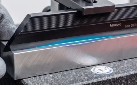 Precyzyjne pomiary 3D z użyciem wzorców Mitutoyo. Błękitne światło uwydatnia idealnie płaskie powierzchnie.