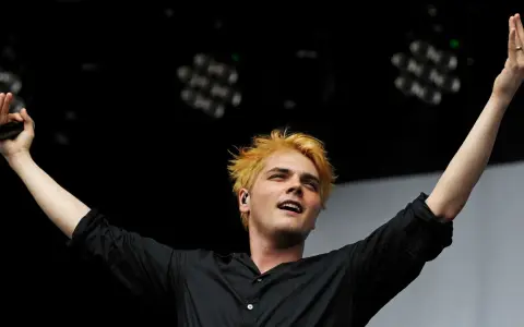 Gerard Way, Sänger des Musikgenres mit E, mit blonden Haaren und erhobenen Armen auf der Bühne.