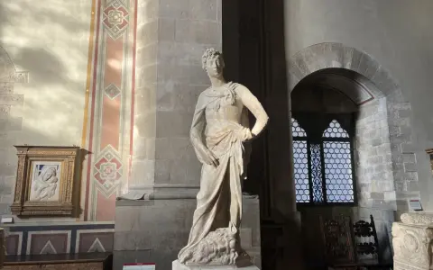 Statue de David par David Verrocchio, debout sur la tête de Goliath, dans un musée.