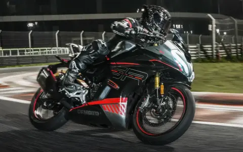 Un pilota in tuta nera sfreccia in pista con la CF Moto 450 SR, puntando alla velocità massima.