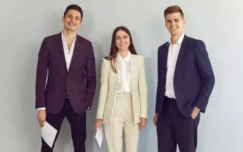 Trzy osoby w eleganckich strojach biznesowych, idealnych, by pokazać, jak się ubrać na rozmowę o pracę.