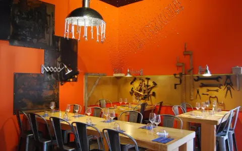 Ambiance industrielle dans un des restaurants de Chambray-lès-Tours. Tables dressées, murs orange vif, luminaires originaux.