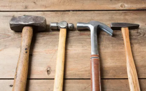 Cuatro martillos de diferentes clases: uno de orejas, uno de bola, uno de carpintero y uno de ebanista, sobre una superficie de madera.