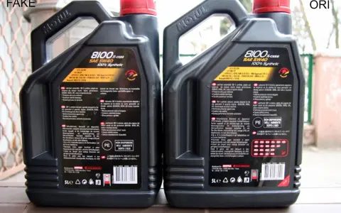 Dwie kanistry oleju silnikowego Motul 8100 X-cess SAE 5W40, jeden oznaczony jako "FAKE", drugi jako "ORI".