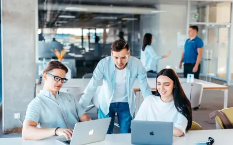 Equipo colabora en un proyecto, usando laptops y aplicaciones informáticas para gestionar la cuenta contable.