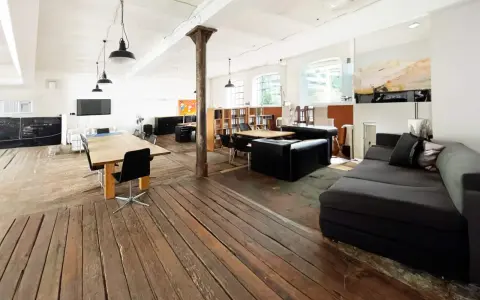Geräumiges Loft mit Holzboden, großen Fenstern, Arbeitsbereich und gemütlicher Sitzecke. Eine perfekte loft definition.