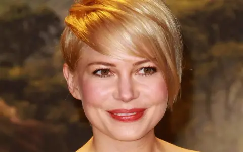 Uśmiechnięta kobieta z okrągłą twarzą i blond fryzurą, z burzą złotych włosów opadających na czoło.