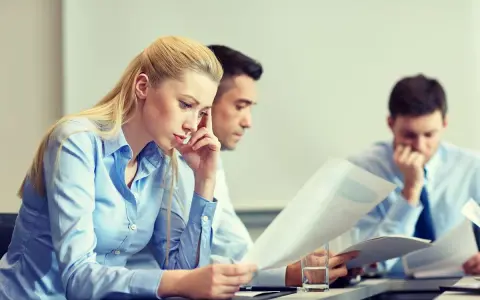 Trzy osoby pochylone nad dokumentami, analizujące dane dotyczące pracowniczego planu kapitałowego.