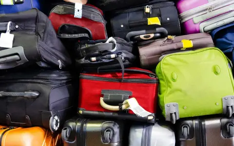 A large pile of various suitcases and bags in different colors, stacked high.
