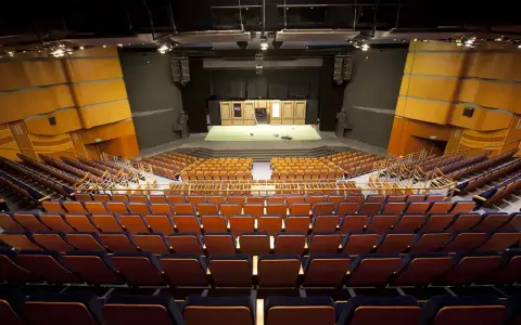 Pusta widownia Teatru Muzycznego im. Danuty Baduszkowej. Pomarańczowe fotele czekają na widzów, scena gotowa na spektakl.