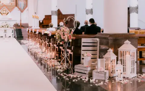 Romantyczna dekoracja kościoła na ślub samemu: płatki róż, świece, latarenki i kwiaty tworzą magiczną atmosferę.
