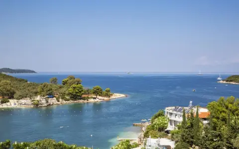 Piękna zatoka w Ksamil, Albania, z turkusową wodą, zielonymi wyspami i białym hotelem. Idealne miejsce na wakacje.