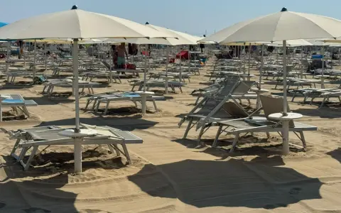 Ombrelloni e lettini pronti per il Ferragosto sulla Riviera Romagnola. La sabbia dorata attende i bagnanti.
