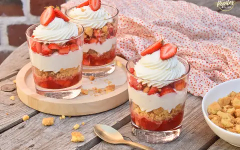 Trois verrines fraise mascarpone, garnies de crème fouettée et de fraises fraîches, sur une table en bois.