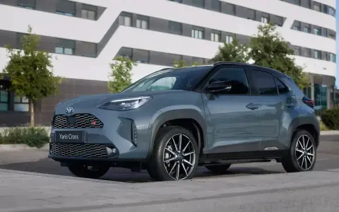 Szary Toyota Yaris Cross hybryda stoi na tle nowoczesnego budynku.
