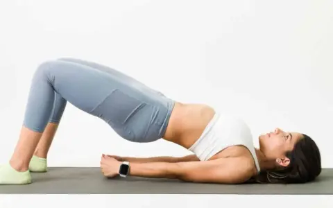 Mujer haciendo puente en colchoneta, ejercicio para fortalecer glúteos y mejorar cómo dormir para que no te duela la espalda.