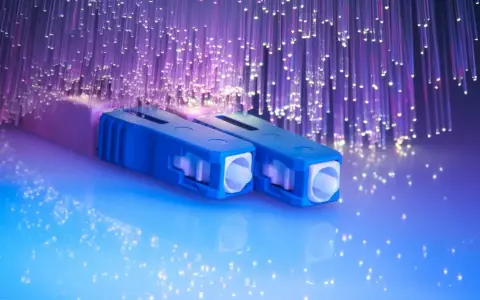 Connecteurs bleus pour télécommunication fibre optique, entourés de fils lumineux violets.