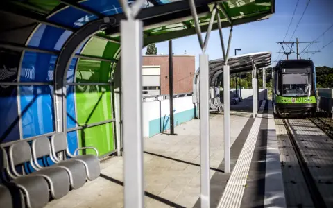 Nowoczesny przystanek tramwajowy w Szczecinie. Zielony tramwaj czeka na pasażerów. Jak dojechać do centrum?