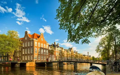 Un paseo por los canales de Amsterdam con adolescentes, disfrutando de las casas históricas y el sol.
