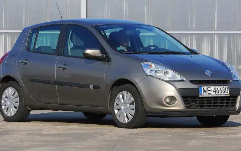 Szary Renault Clio 3 z kierowcą za kierownicą, zaparkowany na zewnątrz.