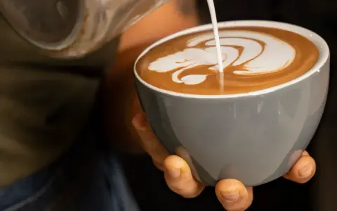 Barista verziert einen Espresso Latte mit Milchschaum. Ein Kunstwerk in der Tasse.