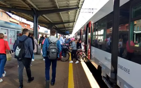 Ludzie czekają na pociąg na stacji w Lęborku. W tle widać budynek dworca i peron.