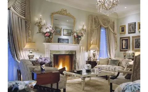 Elegancki salon z kominkiem, lustrem i meblami. Wazon z kwiatami, świece i lampy tworzą przytulną atmosferę. Co to majolika? To ozdobna ceramika, często używana do dekoracji wnętrz.