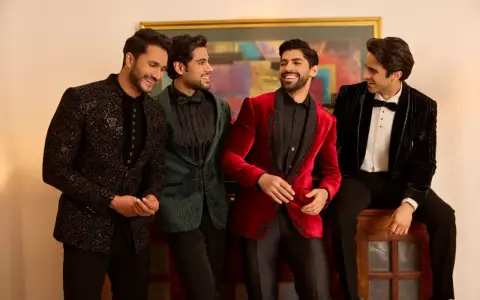 Four men in stylish winter wedding attire, showcasing embellished jackets in black, green, red, and velvet.
