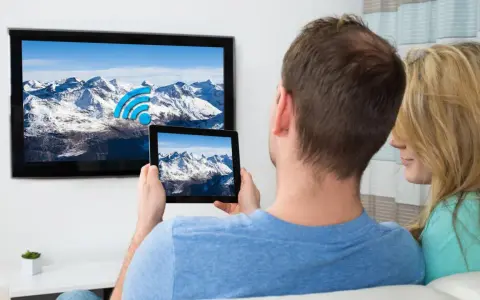 Ein Paar verbindet sein iPad mit dem Fernseher, um die Berglandschaft auf dem großen Bildschirm zu genießen.