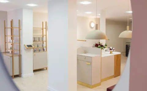 Helle, moderne Kosmetikboutique mit Regalen, Theke und Blumenarrangement.