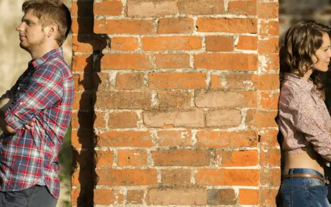 Un homme et une femme se tiennent de part et d'autre d'un mur de briques. Peut-on fixer quelque chose sur un mur mitoyen ?