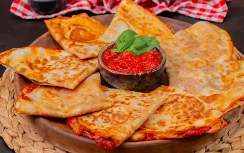 Goldbraune Quesadillas, gefüllt mit geschmolzenem Käse und Tomaten, serviert mit frischem Basilikum. Ein einfaches Quesadillas Rezept für jeden Anlass.