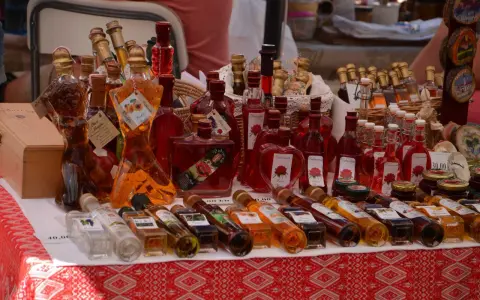 Różnorodne butelki z rakiją, w tym te o fantazyjnych kształtach, prezentują bogactwo smaków. Co to rakija? To tradycyjny alkohol, często owocowy.