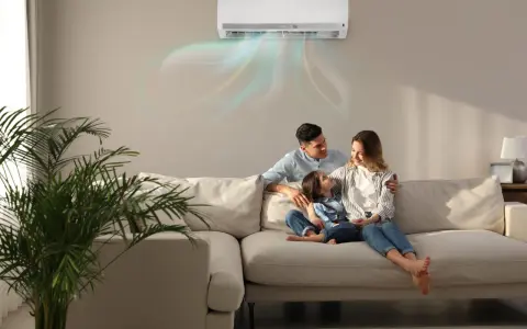 Famiglia felice sul divano, con l'aria condizionata che soffia aria fredda. Scopri come impostare condizionatore aria fredda per un comfort ottimale.
