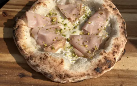 Frisch gebackener Pizzateig mit Mortadella und Pistazien. Ein Genuss, der das Pizzabacken zu einem Erlebnis macht.
