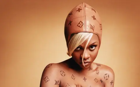 Lil' Kim w skórzanej czapce i z tatuażami Louis Vuitton na ciele.