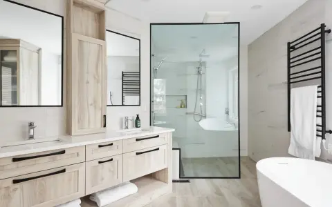 Salle de bain moderne avec double vasque en bois clair, douche vitrée et baignoire îlot. Un design épuré pour une ambiance zen.