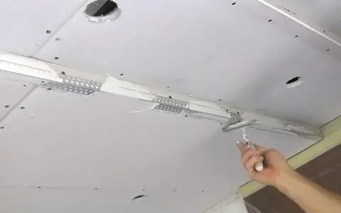Hand spachtelt Rigipsdecke, um eine glatte Oberfläche für den Innenausbau zu schaffen.
