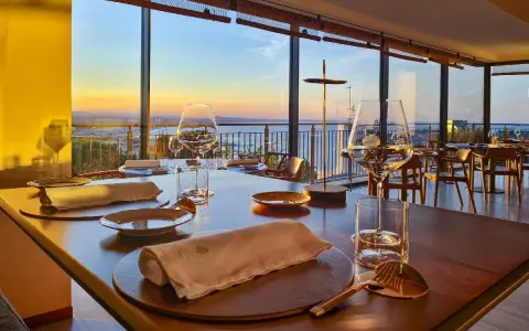 Tavola apparecchiata in un ristorante stellato a Gabicce Monte, con vista sul tramonto sul mare.