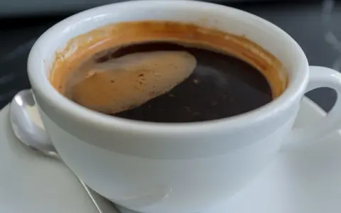 Aromatic coffee in a white cup, a moment to ponder: czy kawa jest zdrowa? The rich crema hints at a complex flavor.