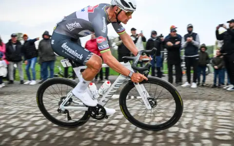 Radfahrer in voller Fahrt auf Kopfsteinpflaster, die Menge jubelt. Van de Poel gibt alles.