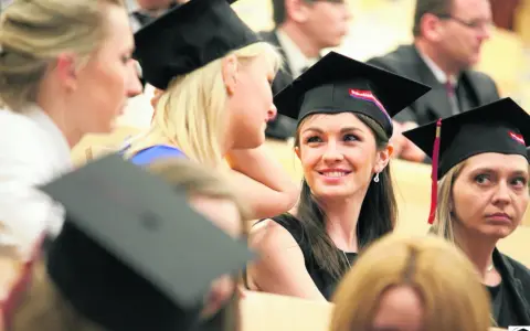 Grupa studentek w togach i biretach podczas uroczystości.